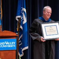 Provost and President smile as Craig Benjamin holds his award